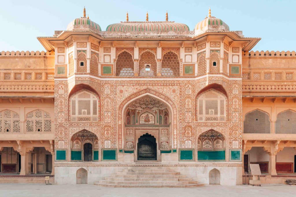 A landscape picture of an ochre passageway surrounded by beautiful Mughal and Rajput inspired designs and archways on all sides.